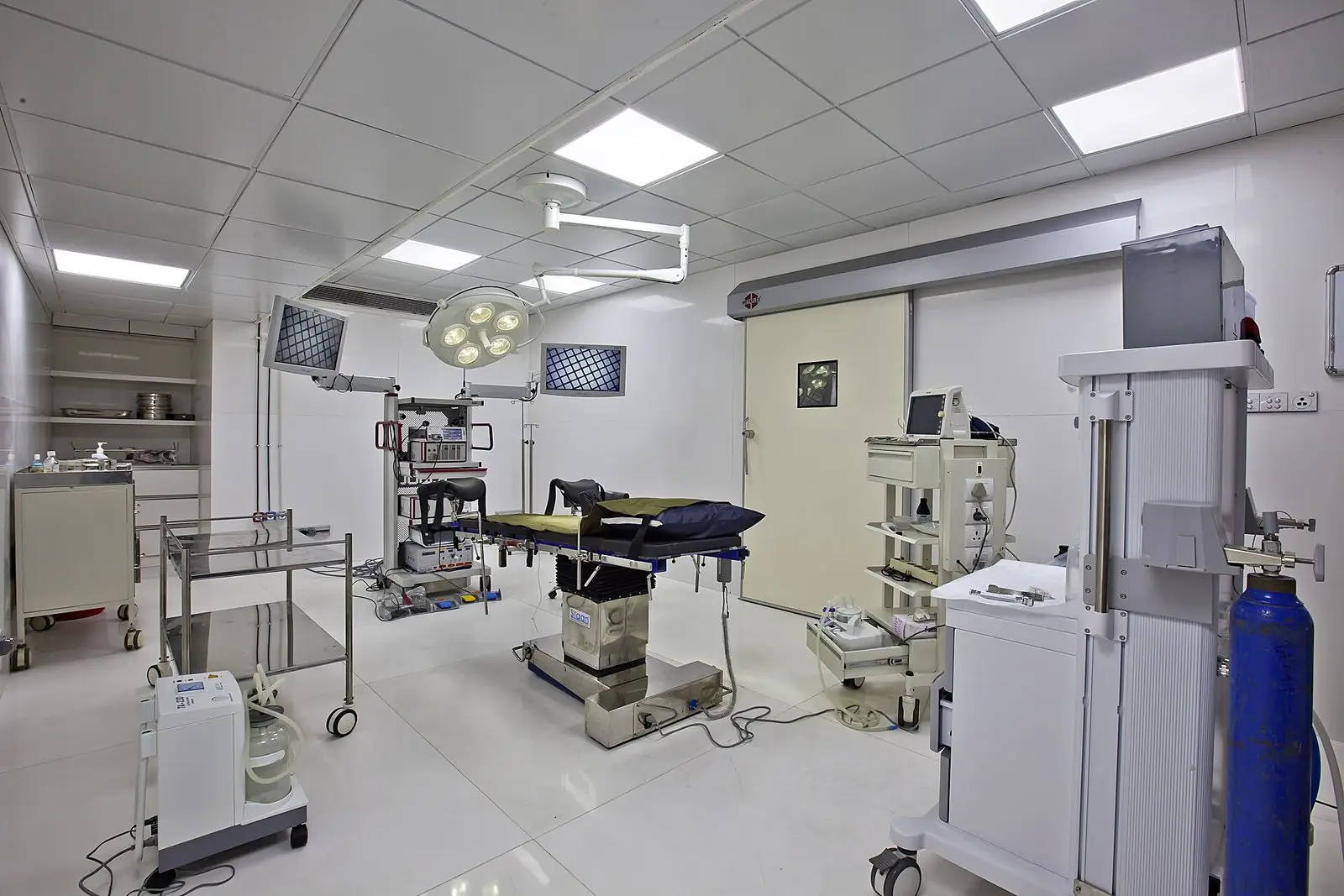 Empty operating theatre with a laparoscopy equipment tower, two video monitors and an operating table